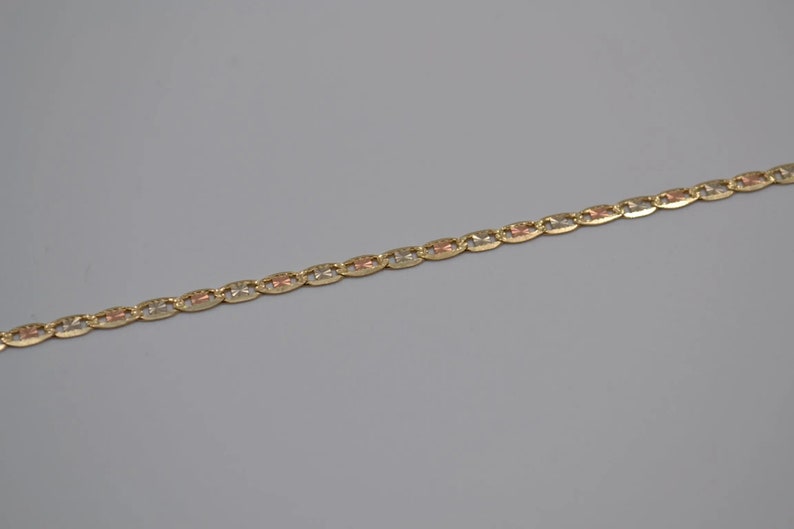 May include: A gold chain necklace with a delicate, patterned design. The chain is made of three different shades of gold, creating a unique and stylish look.