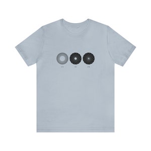 Könnte beinhalten: Hellblaues T-Shirt mit drei schwarzen Spiralmustern und den Zahlen 6/14, 5/16 und 6/16 darunter. Das T-Shirt besteht aus einem weichen, bequemen Material.
