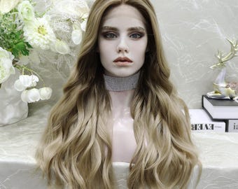 May include: A long, wavy wig with a blend of blonde and light brown tones. The wig features a lace front and is styled with loose curls. A mannequin head displays the wig, with a sparkling choker necklace.