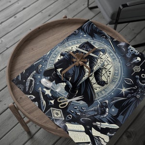 May include: A wrapped gift with a brown ribbon sits on wrapping paper with a dark blue and cream illustration of a cloaked figure with a sword. The paper features various occult symbols and imagery, including knives and a circular design.
