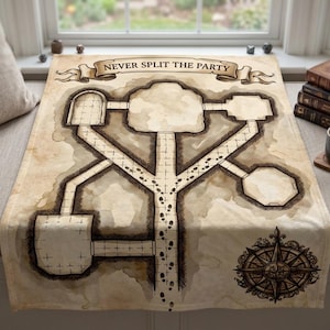 Può includere: Una coperta rettangolare in tessuto con uno sfondo beige in stile pergamena e un'illustrazione a inchiostro marrone scuro di una mappa di un dungeon. Il testo NEVER SPLIT THE PARTY è stampato su uno stendardo in alto, con una rosa dei venti.