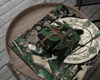 May include: A wrapped gift with a brown ribbon sits atop black wrapping paper with a green and gold fantasy design. The scene includes scissors and tape on a wooden table, with additional wrapping paper featuring similar artwork.