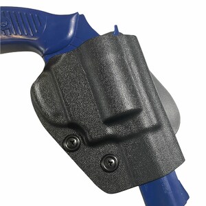 May include: Black, textured holster with two black screws, holding a blue handgun. The holster is designed to securely hold the firearm. The image is set against a white background.