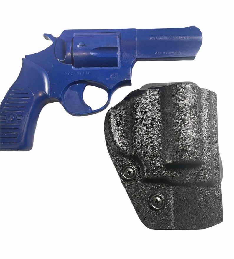 May include: A blue revolver and a black holster are displayed against a white background. The revolver has a dark blue finish. The holster is made of a textured black material and features two visible screws.