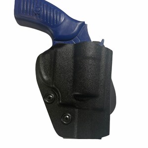 May include: A black, molded polymer holster with a blue handgun grip visible. The holster has a textured surface and is secured with two black screws. The handgun grip is blue and has a ribbed design for grip.