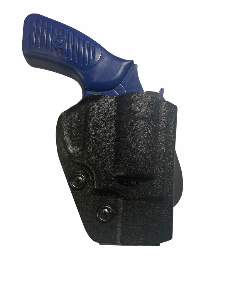 May include: A black, molded polymer holster with a blue handgun grip visible. The holster has a textured surface and is secured with two black screws. The handgun grip is blue and has a ribbed design for grip.