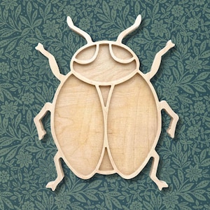 May include: A wooden beetle-shaped tray with a light brown finish. The tray features a detailed cutout design of a beetle, including antennae, legs, and body segments. The background is a dark teal floral pattern.