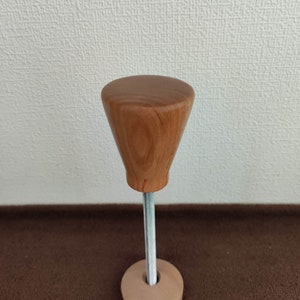 以下が含まれることがあります： 丸い先細りのトップと金属製のロッドが付いた木製シューストレッチャー。ストレッチャーは丸い木製ベースに取り付けられています