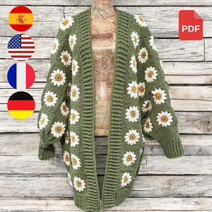 May include: A green crocheted cardigan with a daisy pattern. The cardigan has a long, open front and long sleeves.