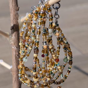 May include: A set of beaded bracelets in shades of brown, gold, and green. The bracelets are made with small, round beads and have silver clasps.