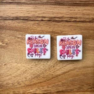 Peut inclure: Deux carreaux carrés blancs avec une inscription rose et orange qui dit "Soyez la raison pour laquelle quelqu'un sourit aujourd'hui !" avec un smiley.