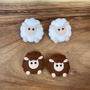 Peut inclure: Quatre boutons en silicone en forme de mouton. Deux sont blancs avec des yeux bruns et deux sont bruns avec des yeux blancs.