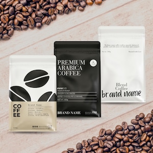 Op de afbeelding: Drie koffiezakken in zwart, wit en beige, met verspreide koffiebonen. De zakken tonen teksten als "Premium Arabica Coffee" en "Blend Coffee." De zakken bevatten 100g en 500g koffie.