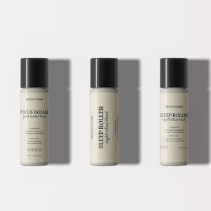 May include: Three essential oil roller bottles with black caps and off-white labels. The bottles are labeled "FOCUS ROLLER fresh herbal blend" and "SLEEP ROLLER night ritual blend". The bottles are approximately 4 inches tall.