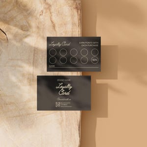 May include: Two black loyalty cards with white text and circular point trackers. One card reads "Loyalty Card" and "Earn points with each purchase." The other card displays the brand name and contact information. The cards are on a light brown surface.