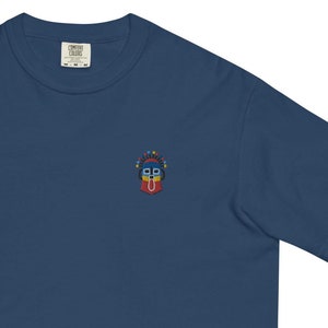 May include: A dark blue t-shirt with a small embroidered design of a colorful face with a red tongue sticking out.