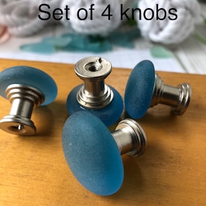 May include: Set of four blue glass cabinet knobs with silver metal bases.  The knobs have a frosted, textured finish.  "Set of 4 knobs" is written in the image.