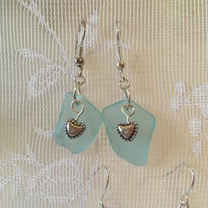 May include: A pair of earrings with light blue glass teardrop-shaped pendants and silver heart charms.