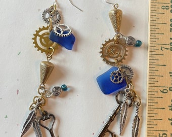 Steampunk earrings with blue glass, hearts, key, gear cogs, feathers.  3 3/4” Long dangle boho charm earrings.Seaglass infused  boho jewelry