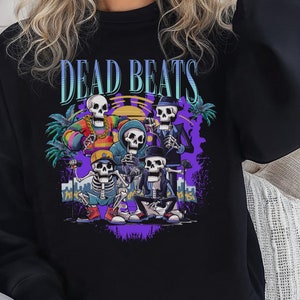 May include: Black sweatshirt with a graphic print of five skeletons playing music. The text "DEAD BEATS" is printed above the skeletons.