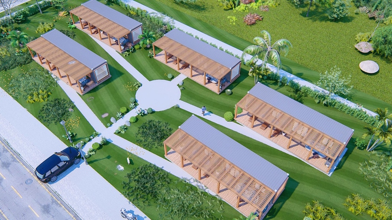 May include: An aerial view of a small village of modern, wooden cabins with white roofs. The cabins are arranged in a circular pattern on a grassy lawn with a paved walkway leading to each cabin. A car is parked on the street in front of the village.