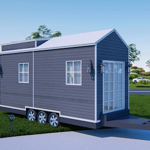 May include: A gray and white tiny house on wheels with a large window and a white door. The house has a white roof and a gray siding. The house is sitting on a grassy lawn.