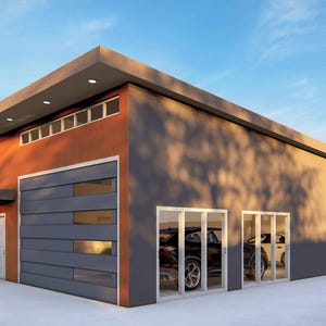 May include: A modern, two-car garage with a gray and orange exterior. The garage has a large, gray sectional garage door and two sets of glass doors. The garage is surrounded by a concrete driveway and a grassy lawn.