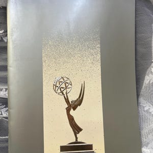 May include: A silver award with a winged figure holding a globe. The award is on a black base and has a silver finish.