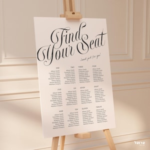 May include: A white seating chart on a wooden easel, featuring the words "Find Your Seat" in black script. The chart lists names in columns, suitable for a wedding or event. The phrase "Saved just for you!" is written in script.