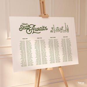 Puede incluir: Un plano de asientos de boda blanco sobre un caballete de madera. El gráfico presenta el texto "Your Seat Awaits" en escritura verde, con asignaciones de mesa y nombres de invitados. También hay ilustraciones decorativas de comida y bebida.