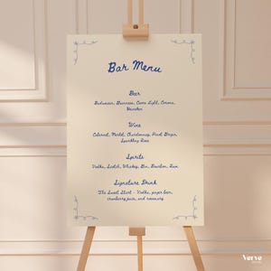 Può includere: Un menu bar color crema su un cavalletto di legno. Il menu, scritto in blu, elenca birra, vino, liquori e un drink speciale. Decorazioni blu sono in ogni angolo. Il cavalletto è su uno sfondo neutro.