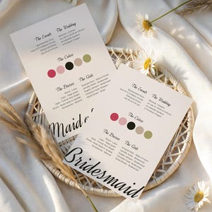 Könnte beinhalten: Zwei Hochzeitseinladungskarten mit Veranstaltungsdetails und Farbmustern, mit den Wörtern "Brautjungfer" und "Maid of Honor". Die Karten liegen auf einem geflochtenen Korb, mit Gänseblümchen und Ziergras.