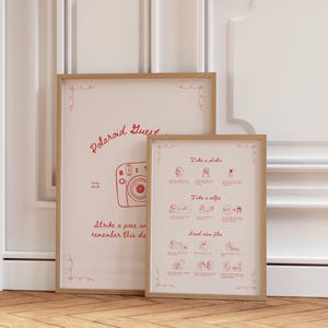 May include: Two framed prints with a light wood finish. The larger print reads "Polaroid Guest Book" with a camera illustration and the text "Strike a pose and help us remember this day forever!" The smaller print has photo instructions.