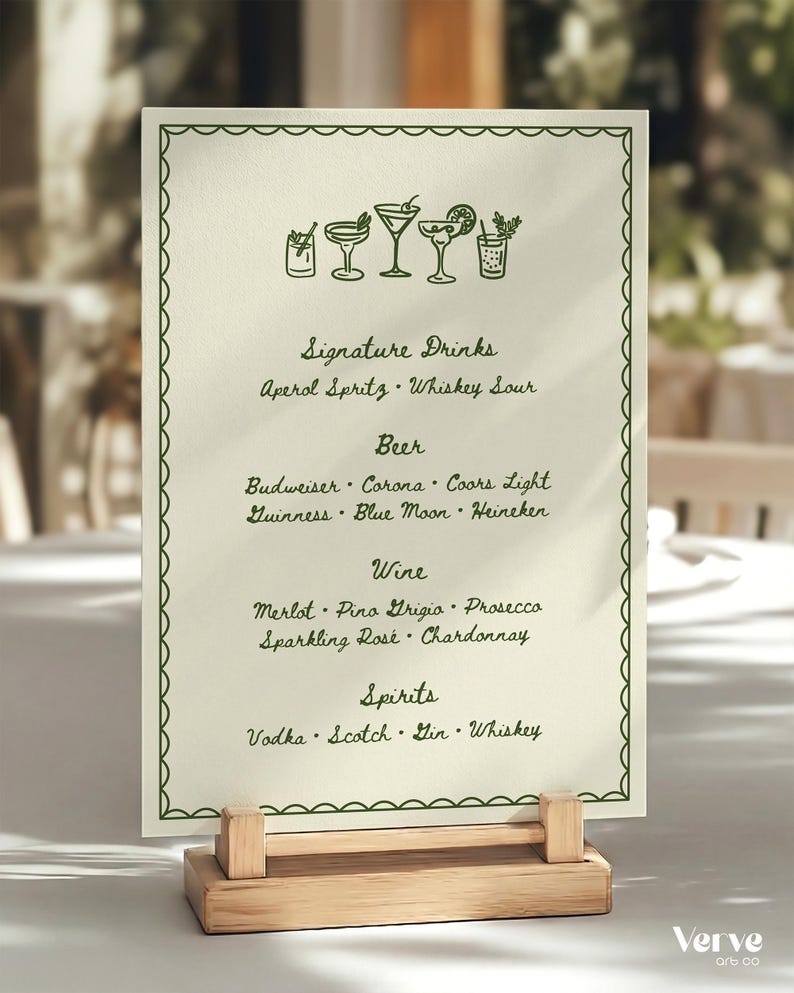 A cream-colored menu card with a hand drawn green border and drink illustrations. The menu lists signature drinks, beer, wine, and spirits. The card is held by a small, light-colored wooden stand.
