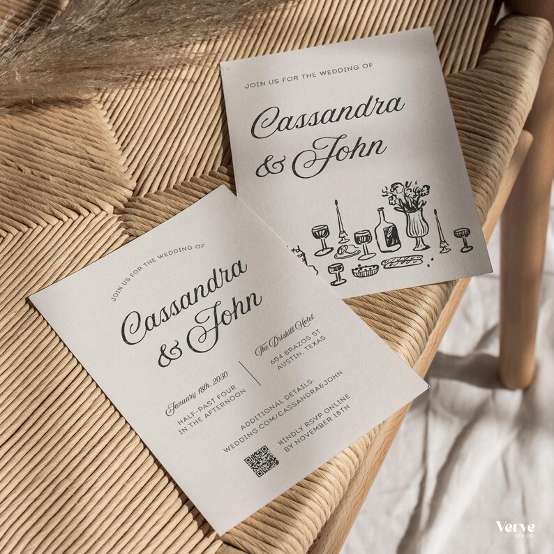 May include: Two off-white wedding invitations with black script. The text reads "Join us for the wedding of Cassandra & John." One card includes the date, time, and location. The other card features illustrations of glassware and a vase of flowers. The invitations are on a woven surface.