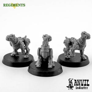 May include: Three grey miniature robotic dog figurines on black circular bases. The dogs have detailed mechanical features, including segmented bodies, and are posed in different positions. The word "REGIMENTS" is in green at the top left.