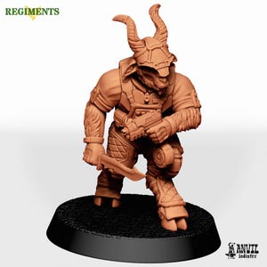 May include: A terracotta-coloured miniature figurine of a goat-headed humanoid warrior wearing tactical gear, a helmet with horns, and quilted leg armour. The figure holds a small firearm in one hand and a curved blade in the other, standing on a black base.