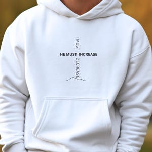 May include: White hoodie with a black graphic print that reads "I must decrease, He must increase".