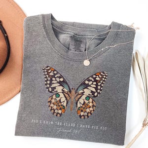 May include: Gray t-shirt with a butterfly graphic and the text "For I know the plans I have for you, Jeremiah 29:11".