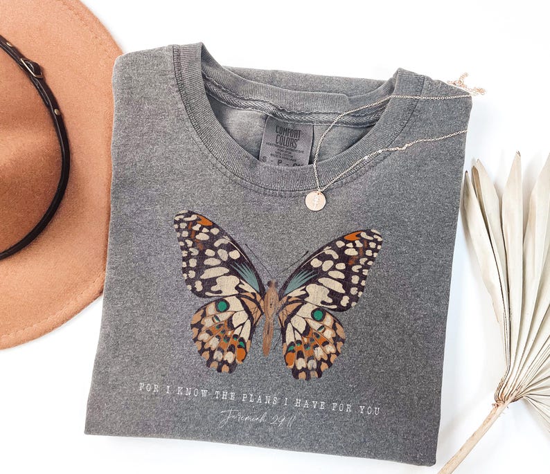 May include: Gray t-shirt with a butterfly graphic and the text "For I know the plans I have for you, Jeremiah 29:11".