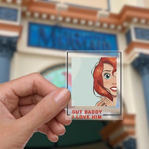 May include: A clear plastic sticker with a cartoon image of Ariel from The Little Mermaid. The sticker has the text "But Daddy I Love Him" printed on it.