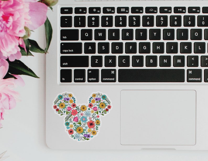 May include: A floral Mickey Mouse design sticker on a laptop. The sticker is made up of colorful flowers and leaves.