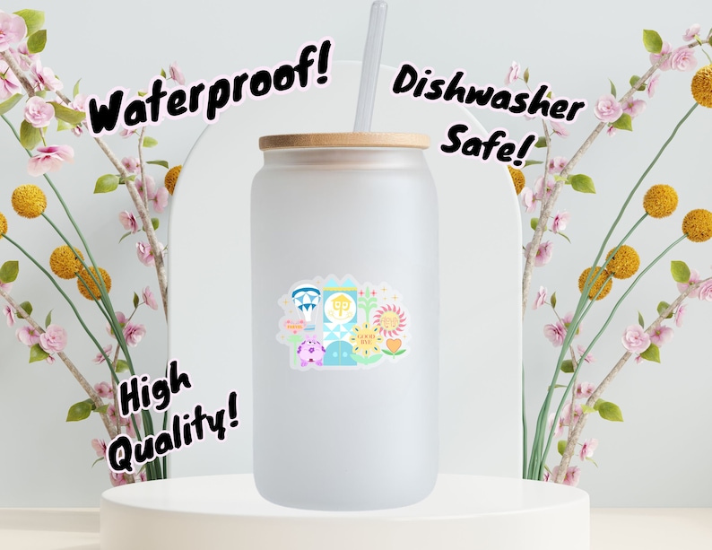 May include: A frosted glass tumbler with a colorful sticker featuring a cartoon illustration of a theme park. The tumbler has a bamboo lid and a straw. The text "Waterproof!" is in the top left corner, "Dishwasher Safe!" is in the top right corner, and "High Quality!" is in the bottom left corner.
