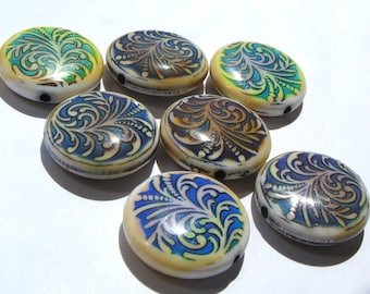 May include: Seven round, iridescent glass beads with a white base and blue, green, and gold swirling patterns. The beads are arranged in a circle on a white surface.