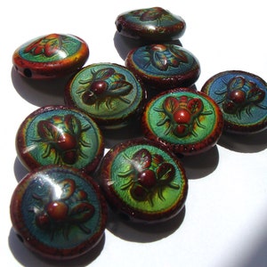 May include: A collection of ten round, iridescent glass beads with a raised design of a fly. The beads are in shades of green, blue, red, and brown.