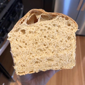 May include: A close-up of a loaf of freshly baked bread, showing the soft, airy crumb and golden-brown crust.