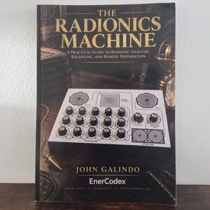 May include: A book titled The Radionics Machine: A Practical Guide to Radionic Analysis, Balancing, and Remedy Preparation by John Galindo. The cover features a white electronic device with black knobs, dials, and a stick pad.