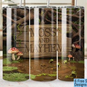 May include: A stainless steel tumbler with a design of a wooden sign that says "Moss and Mayhem" with mushrooms, vines, and frogs on a mossy green background.