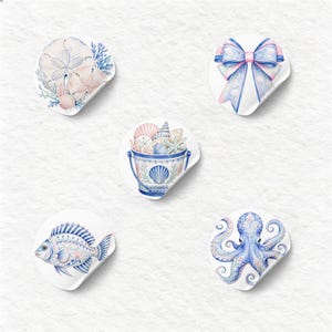 A collection of soft watercolor coastal elements, including a striped swimsuit, a bucket of seashells, nautical ropes, a lighthouse, a pelican, and a sand dollar arrangement, all rendered in serene blues, pinks, and white. This image captures the essence of a tranquil beach vacation.