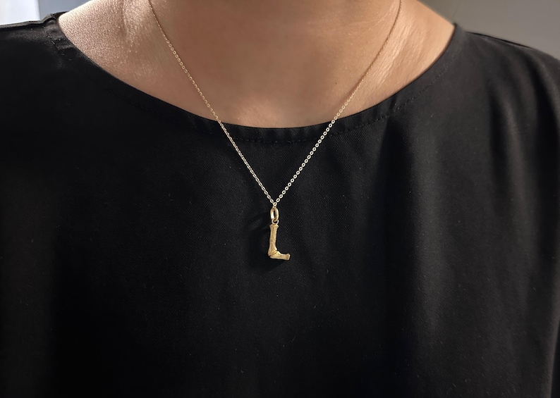May include: A gold chain necklace with a gold letter L pendant.